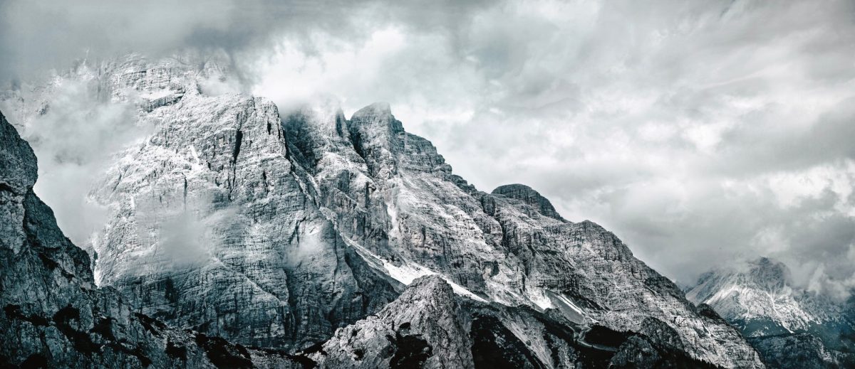 Von Schnee bedeckte Berglandschafr, die von Nebel umgeben ist.