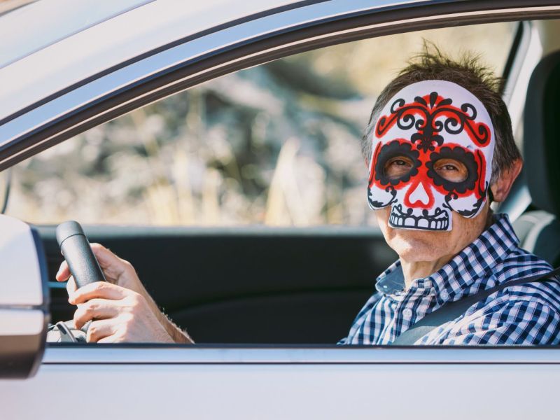 Man mit Halloween-Maske im Auto.