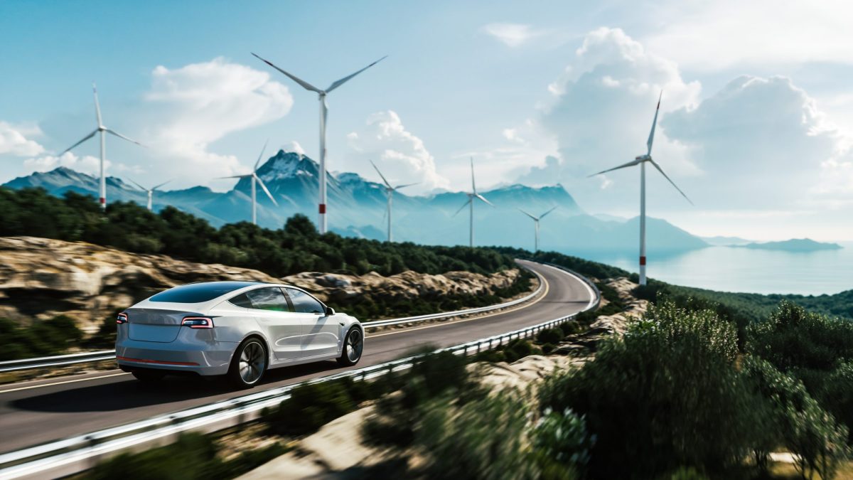 Elektroauto auf einer Autobahn mit Windrädern im Hintergrund.