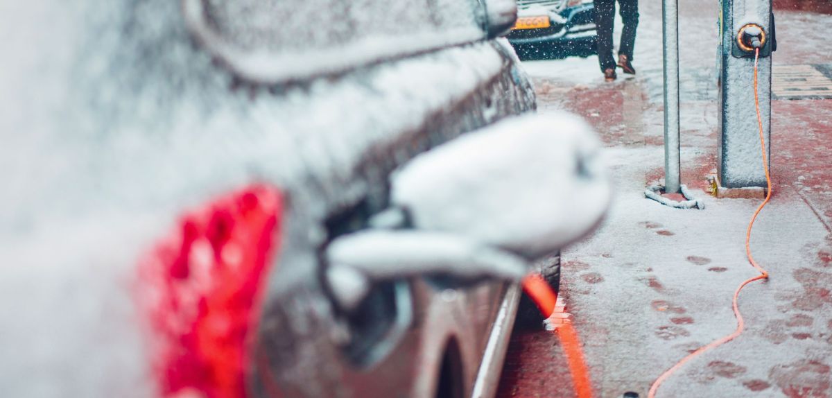 Schneebedecktes Elektroauto an einer Ladesäule