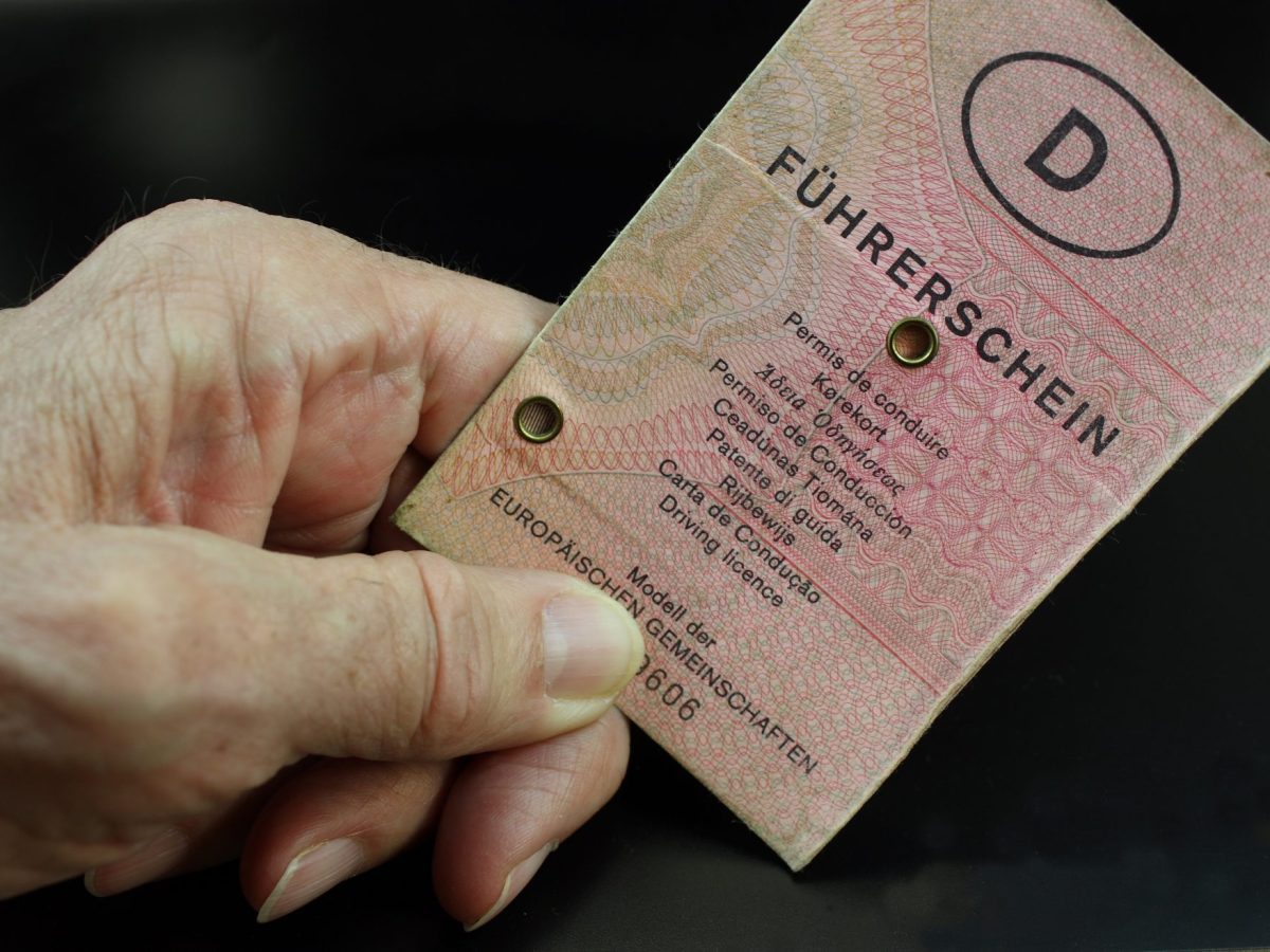 Hand einer älteren Person hält altes Führerschein-Dokument in der Hand.