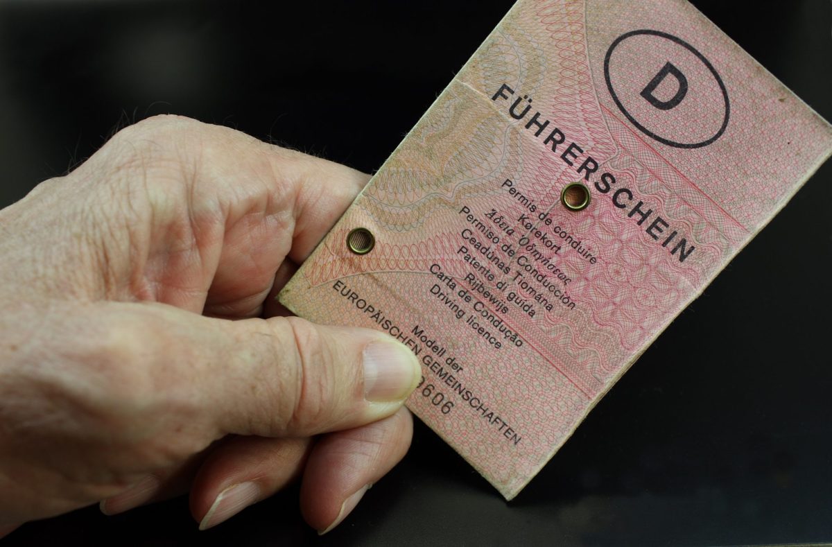 Hand einer älteren Person hält altes Führerschein-Dokument in der Hand.