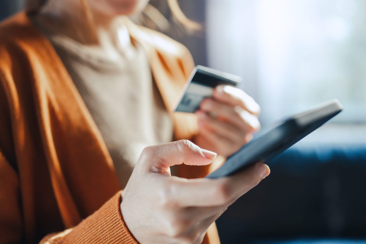 Eine Person hält in der einen Hand ein Handy und in der anderen Hand eine Bankkarte