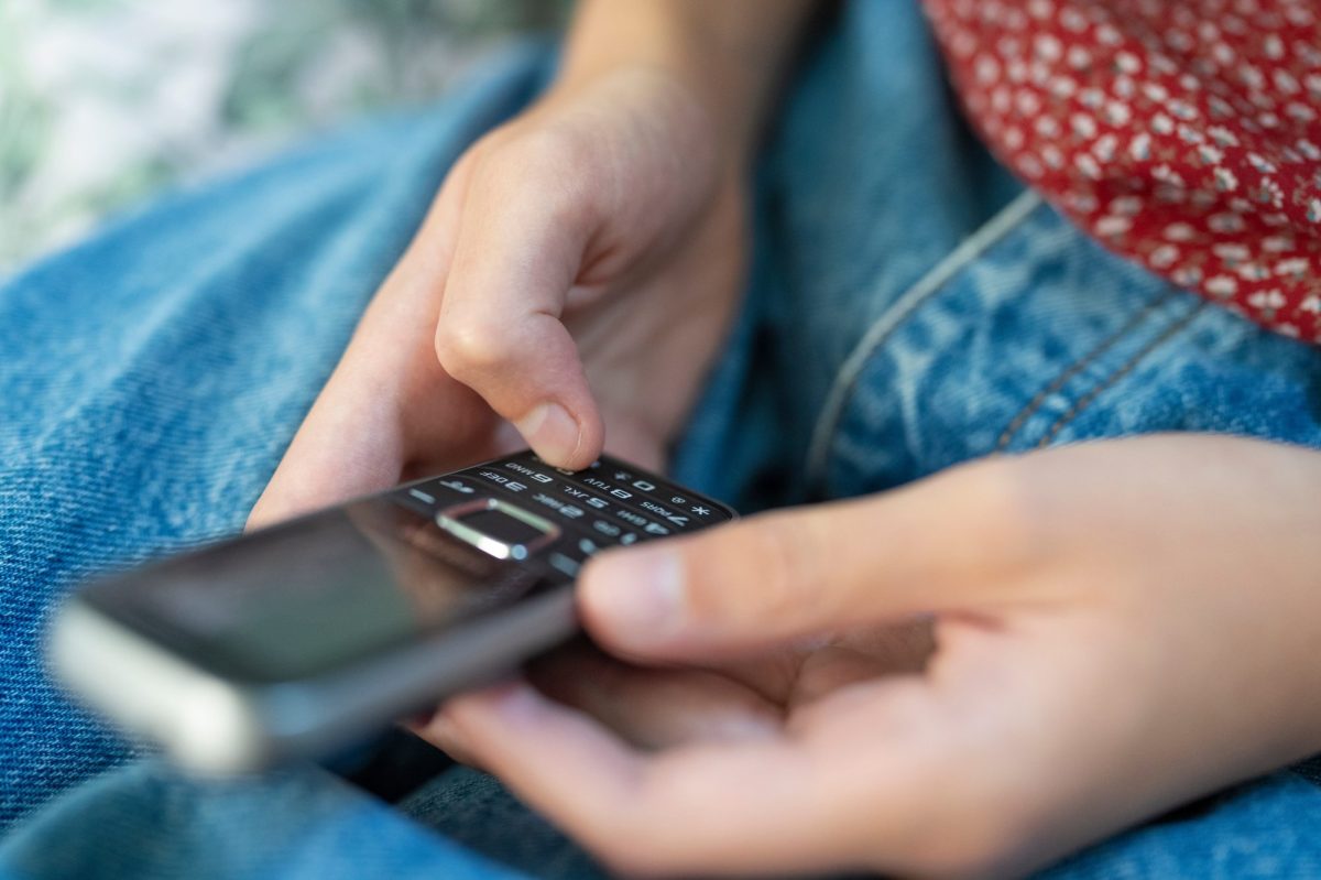 Person mit einem "Dumbphone" in der Hand.