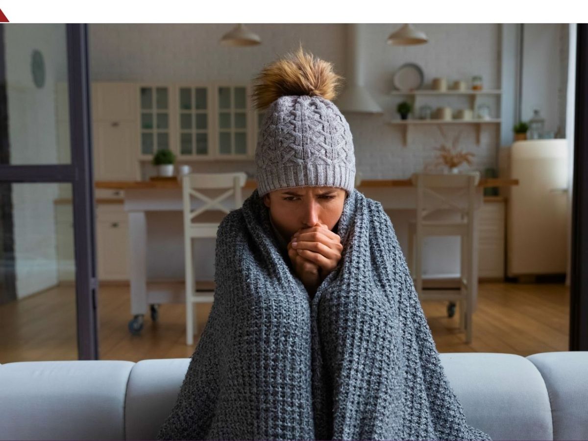 Frau sitzt in eine Decke gehÃ¼llt auf einem Sofa