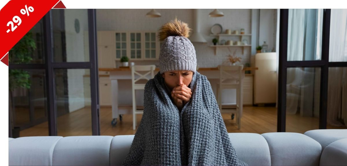 Frau sitzt in eine Decke gehÃ¼llt auf einem Sofa