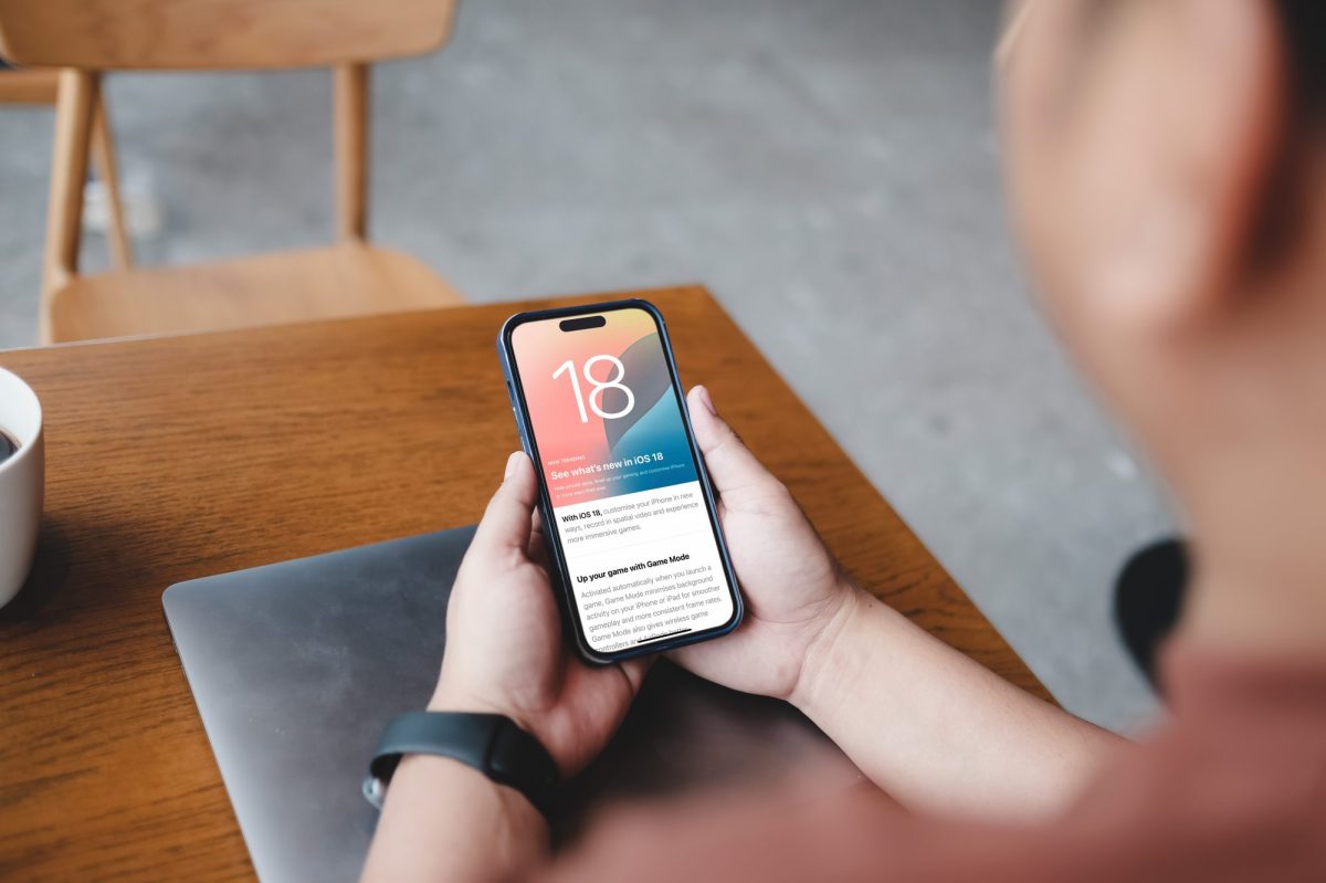 Person hÃ¤lt ein iPhone in der Hand, auf dem iOS 18 geladen ist.