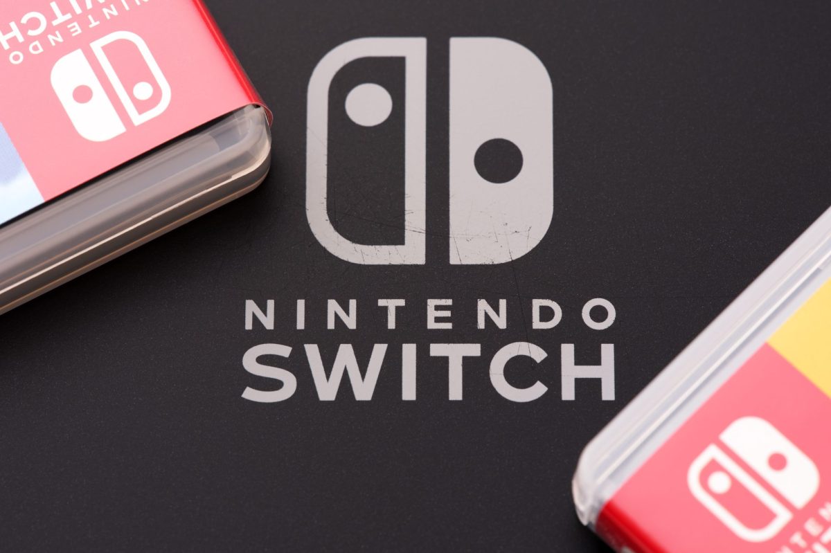 Nintendo Switch-Logo auf dunklem Untergrund. Daneben liegen zwei Nintendo Switch-Spiele.