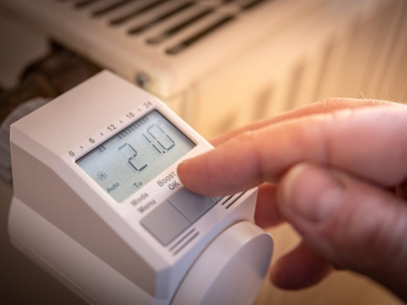 Person stellt smartes Thermostat an einem HeizkÃ¶rper ein.