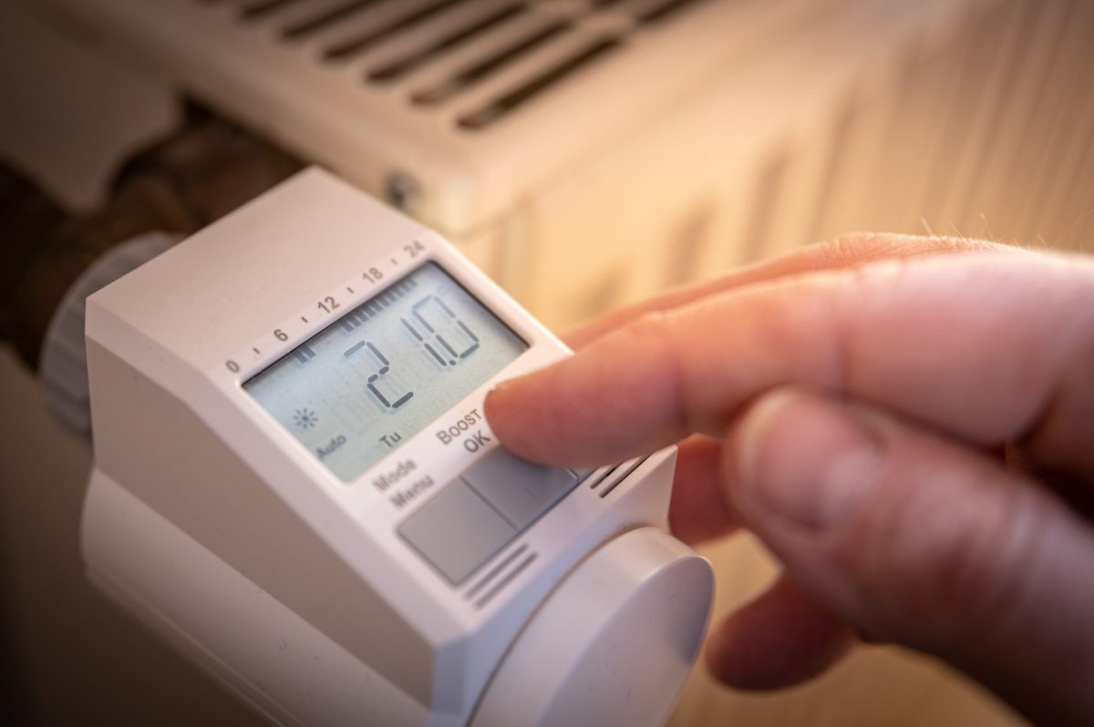 Person stellt smartes Thermostat an einem HeizkÃ¶rper ein.