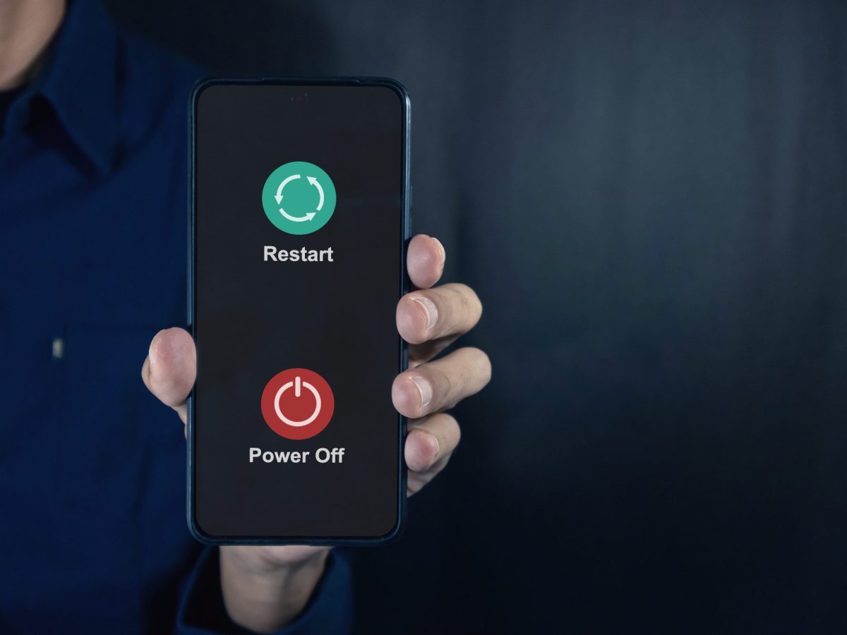 Eine Person hÃ¤lt ein Handy in der Hand. Auf dessen Display werden die Optionen angezeigt, das Handy auszuschalten oder neu zu starten.