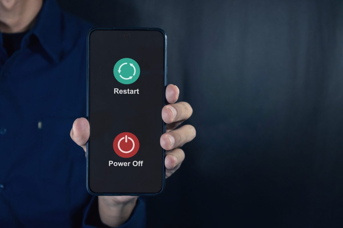Eine Person hÃ¤lt ein Handy in der Hand. Auf dessen Display werden die Optionen angezeigt, das Handy auszuschalten oder neu zu starten.