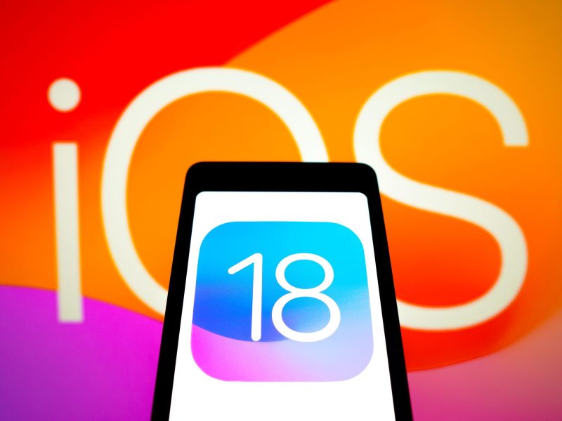 iOS 18-Logo auf einem Smartphone-Display.