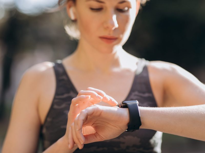 Frau tippt auf eine Apple Watch an ihrem Handgelenk.