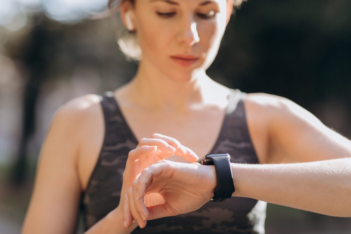 Frau tippt auf eine Apple Watch an ihrem Handgelenk.