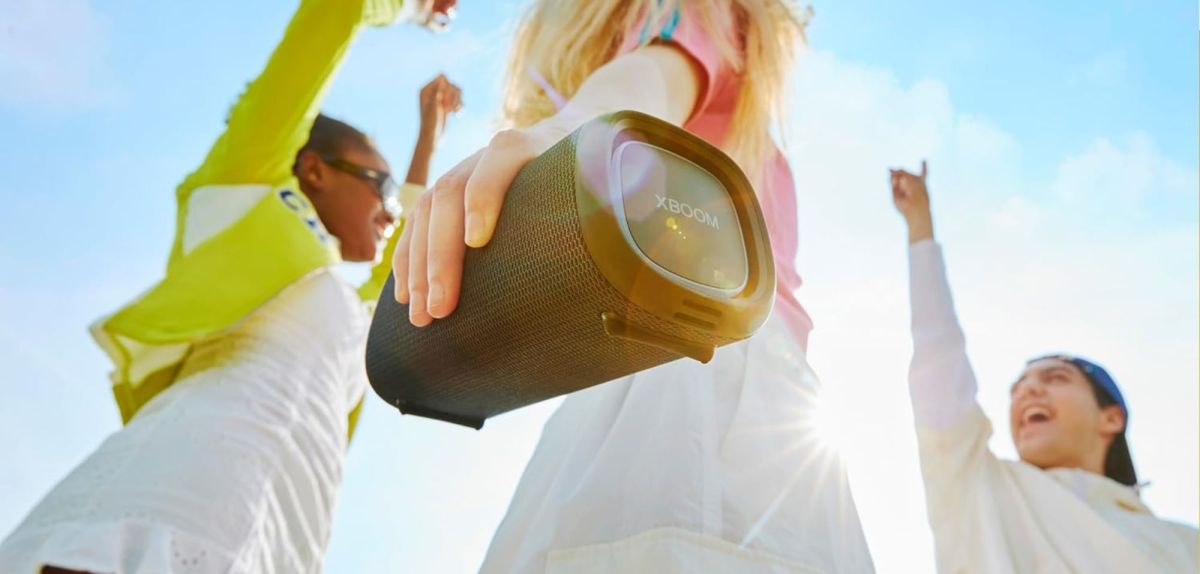 Personen tanzen mit einer Bluetooth-Box in der Hand.