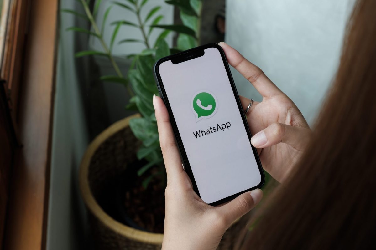 HÃ¤nde halten iPhone mit WhatsApp-Symbol darauf fest.